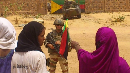 er unge Tuareg kvinner vifter med flaggene til Azawad foran en fransk soldat som står vakt foran en leir til de maliske militære avvist av Kidal's sivilbefolkningen.